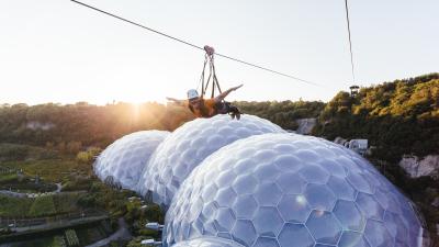 Woman on zip wire above Eden Project Biomes